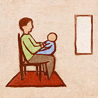 A man sitting in a chair holding a baby on his lap, with a window off to the side.
